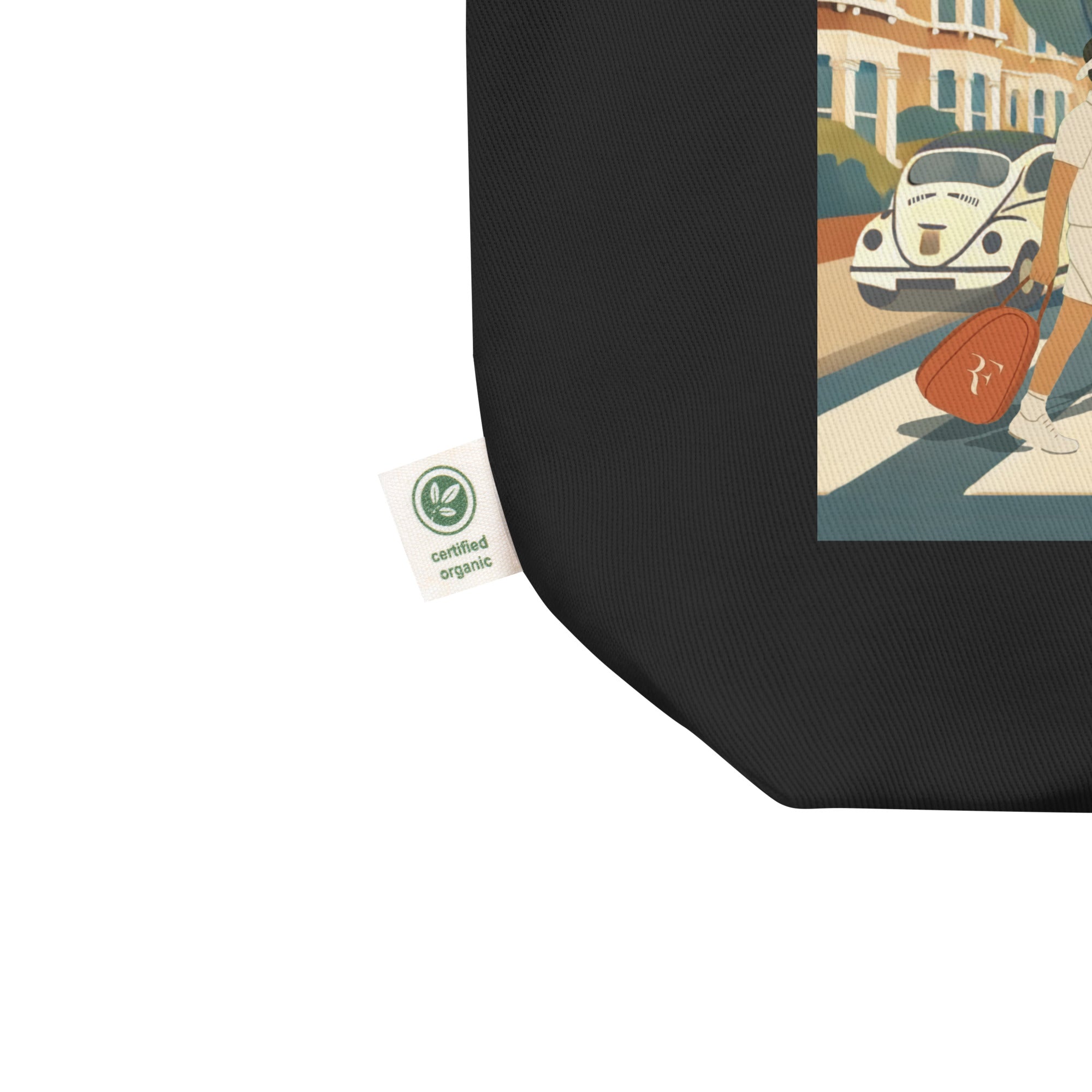 Close-up detail: black organic cotton tote bag showing “certified organic” side tag and a corner of the “Big 4 Crossing” illustration print